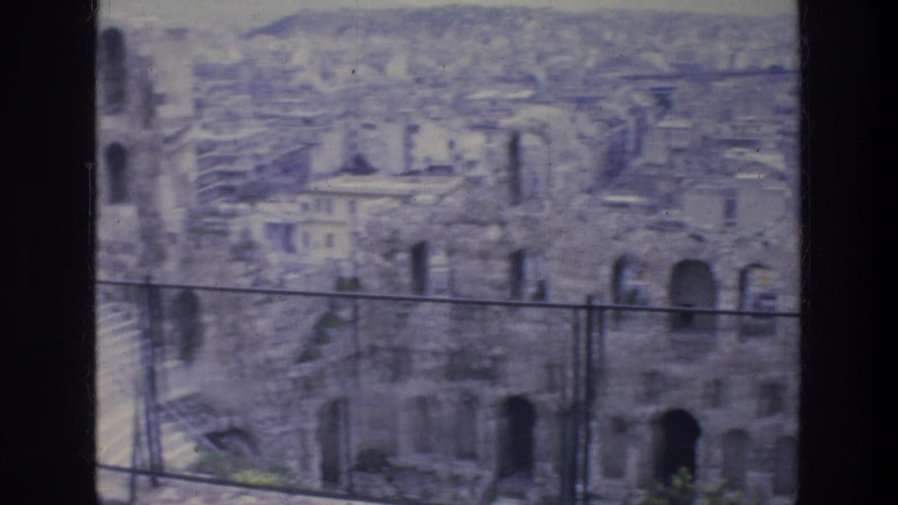 1976 Athens travel footage frame showing weathered stone arches and dense city buildings beyond, viewed with soft 8mm focus.