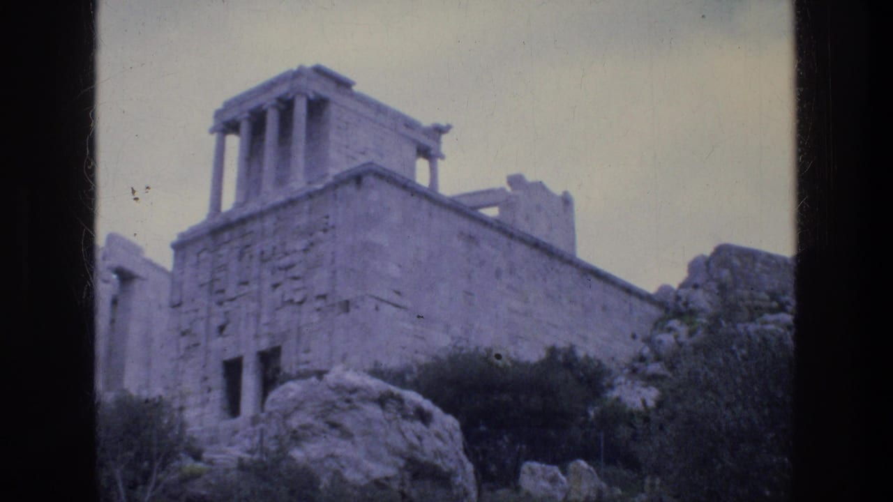 1976 8mm travel frame showing weathered classical stone ruins in Athens, with columns above rocks and shrubs.