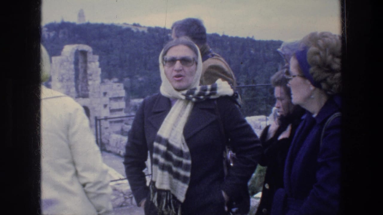 1976 Athens home-movie frame of adult tourists near ancient stone ruins, with headscarves, coats, and sunglasses visible.