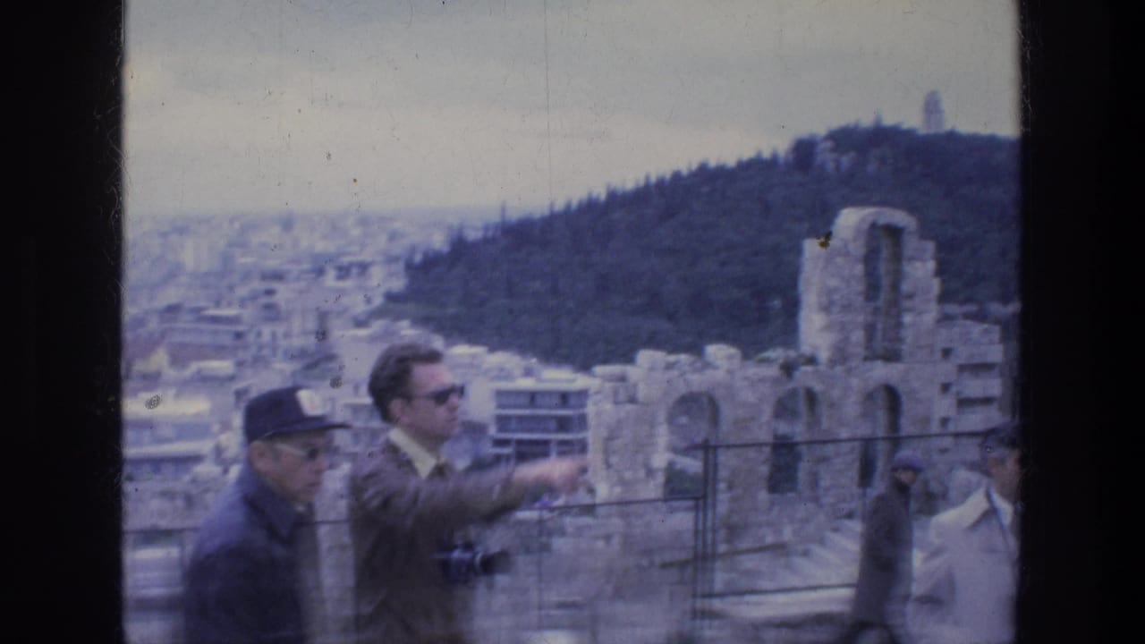 Athens sightseeing frame with tourists beside ancient stone remains, a wooded hill and city buildings beyond.