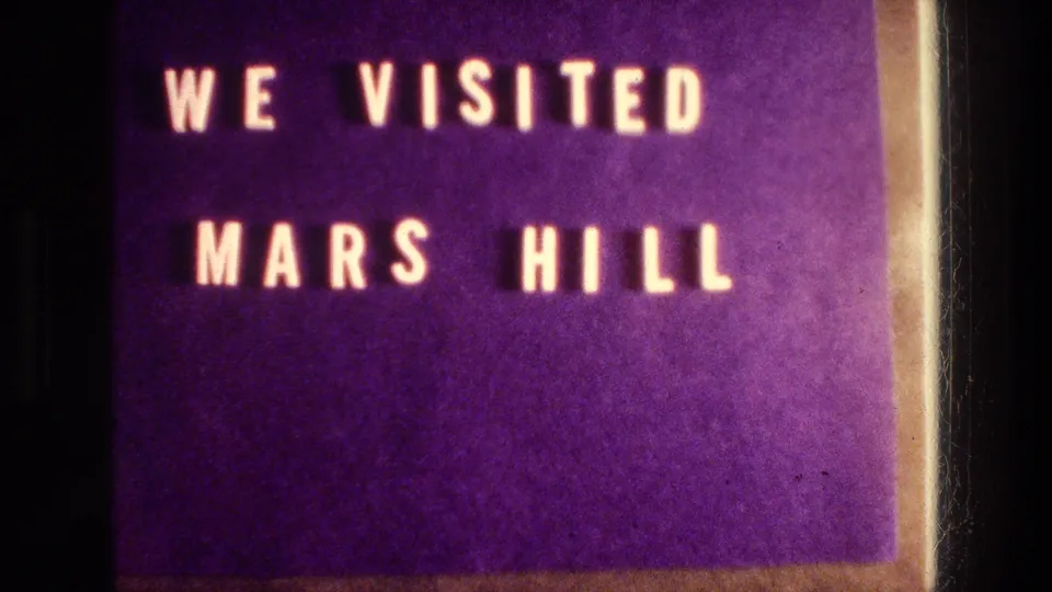 8mm home-movie title card repeating WE VISITED MARS HILL against a purple background with visible film edge.