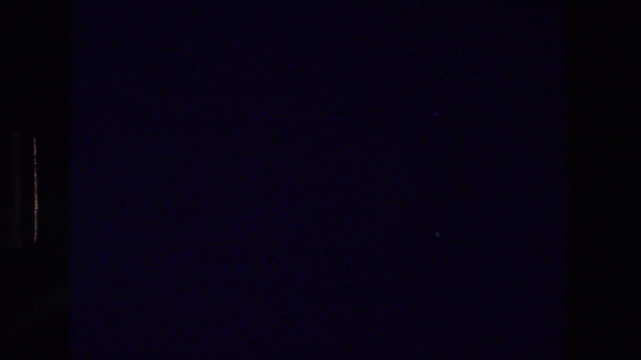 Dark underexposed frame with partial film gate and faint blue image area.