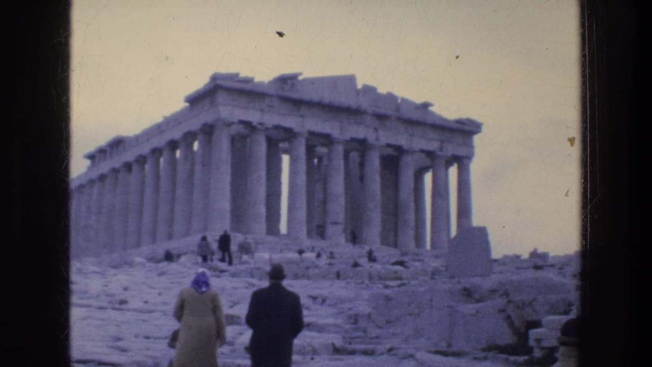 Tourists walk toward the Parthenon across stone ruins under a pale sky.