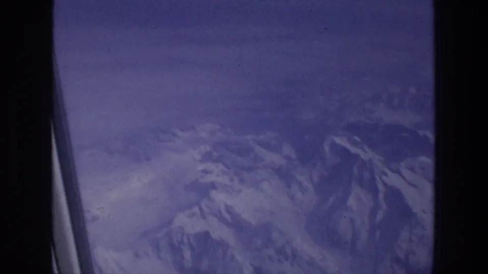 Final frame of the 1976 8mm aerial view, showing hazy snow-covered ridges through the aircraft window frame.