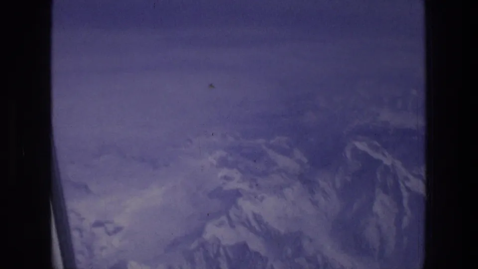 The lower frame shows a softer, darker 8mm view of snowy mountains from an airplane near the Greece travel context.