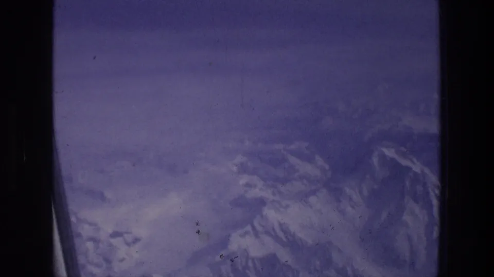 A final 1976 8mm frame holds on snow-covered ridges below the aircraft window in the Athens, Greece travel metadata context.