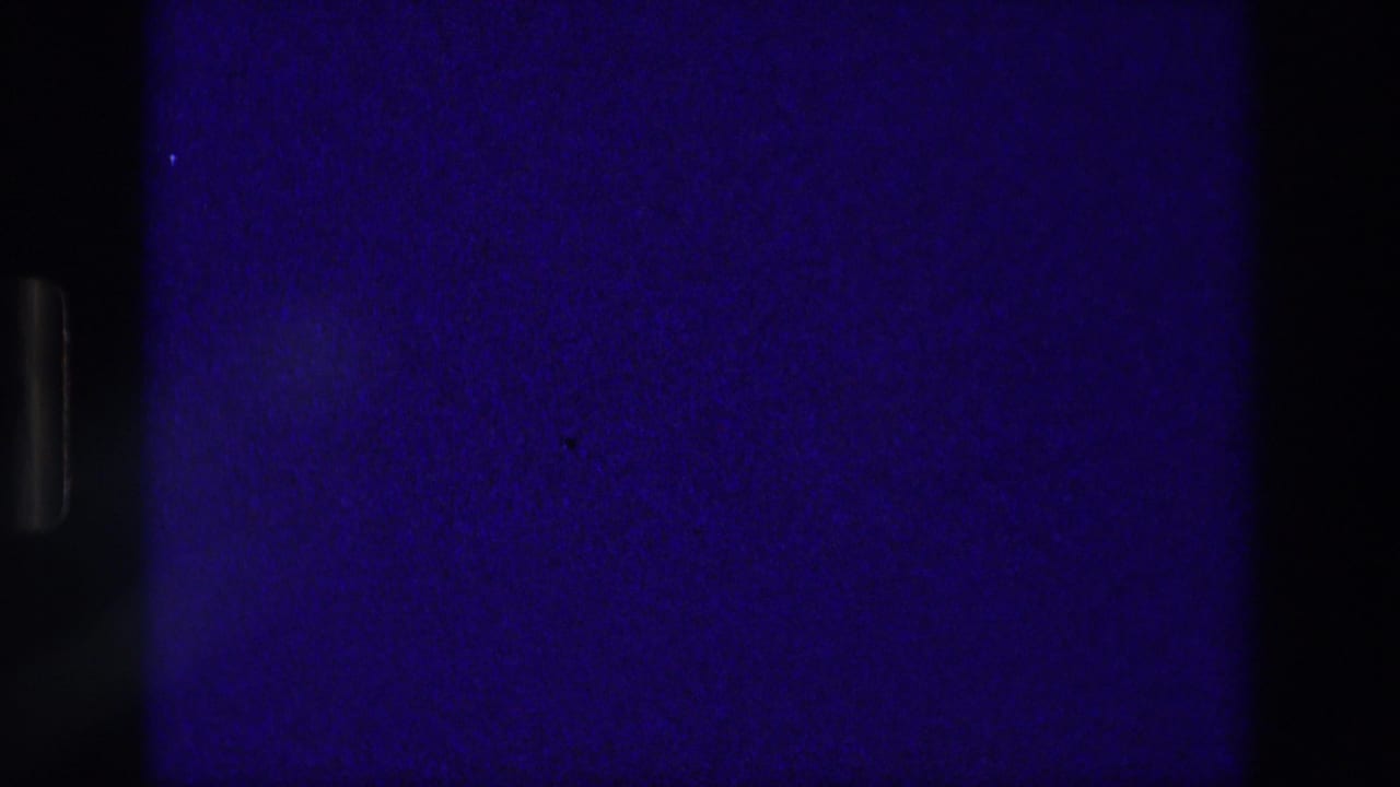 Dark blue and black film area beside a partial reddish plaque frame.