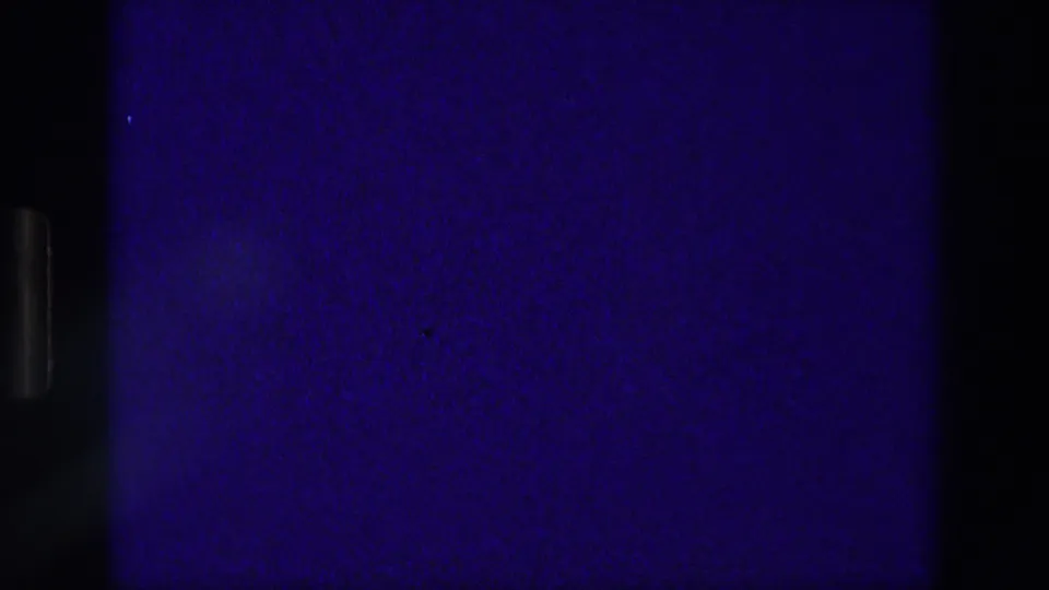 A 1976 8mm Athens frame shows mostly dark border and blue-tinted film area beside the edge of a reddish religious plaque shot.