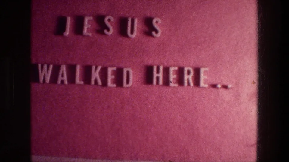A close 1976 Athens 8mm view of a reddish plaque with raised white lettering reading Jesus walked here.