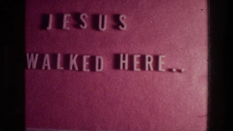A soft 8mm close-up from Athens in 1976 shows the embossed phrase Jesus walked here on a reddish textured plaque.