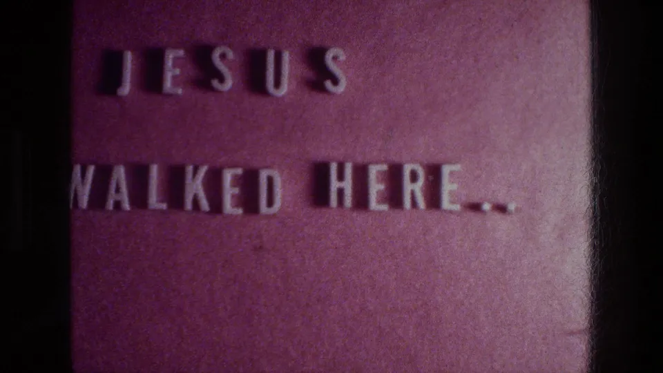 1976 Athens home-movie title card on a red background with white block letters reading JESUS WALKED HERE.