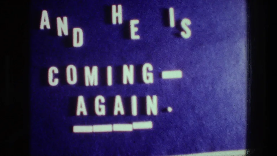 1976 Athens 8mm frame showing a blue religious title card with white block letters and underline marks.