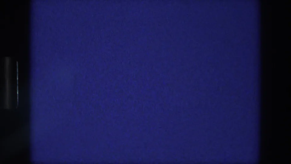Dark blue section of the 1976 Athens 8mm reel, showing black frame edges, grain, and projector-like flicker.