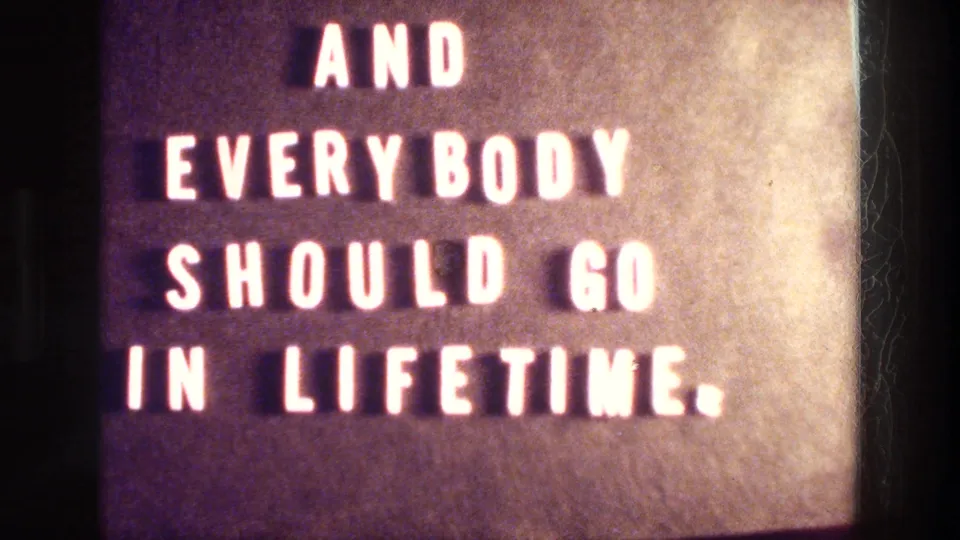 1976 Athens reel title card with white block text reading AND EVERYBODY SHOULD GO IN LIFETIME on a dark textured background.