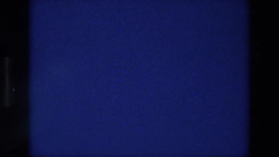 1976 Athens 8mm frame where the sign has mostly cleared, leaving a blue field with film-edge shadows and grain.