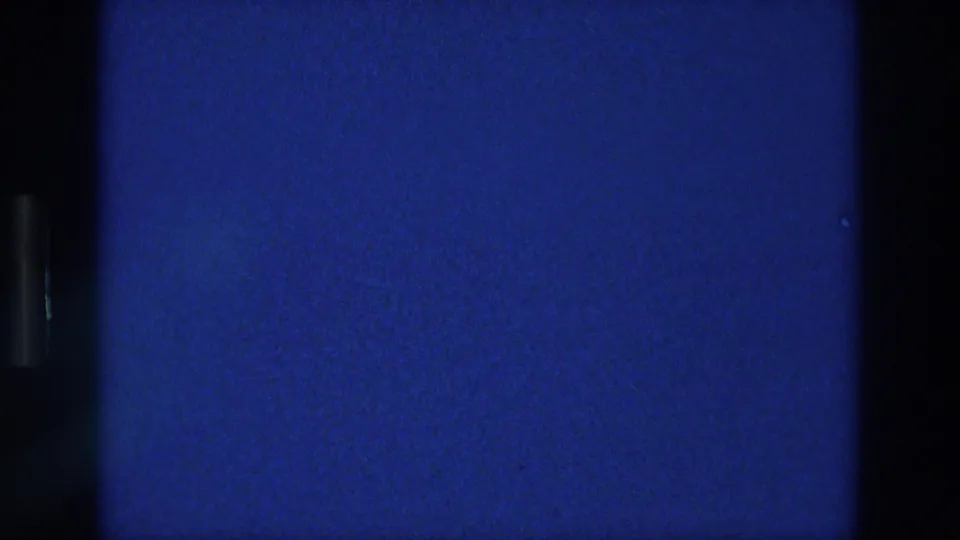 1976 Athens 8mm frame showing a blue field, dark film borders, and the textured grain of the scanned reel.