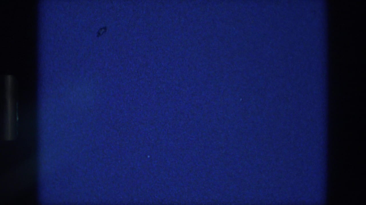 Blue 8mm frame from the Athens 1976 reel, with a dark vertical border and textured film grain.