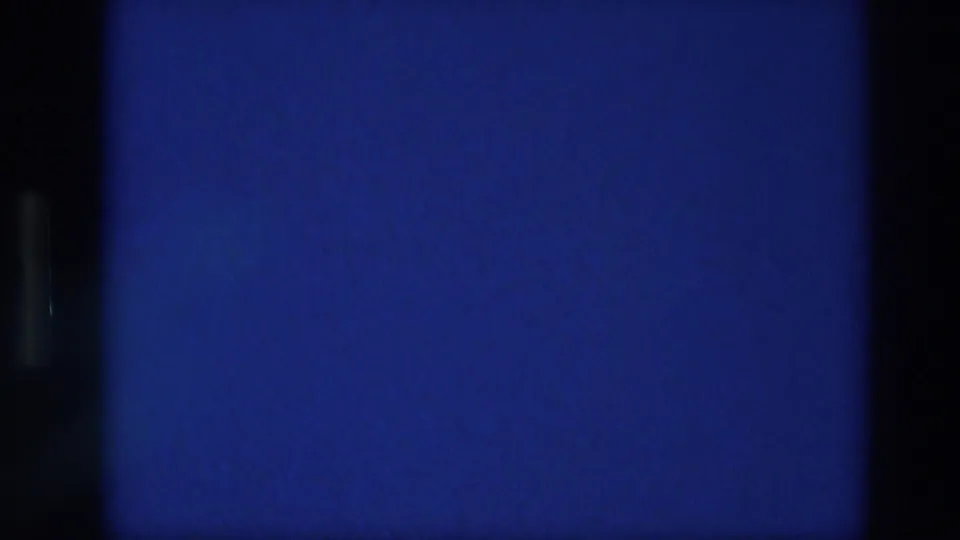 Blue home-movie film artifact with dark vertical borders, sprocket-edge shapes, and aged grain texture.