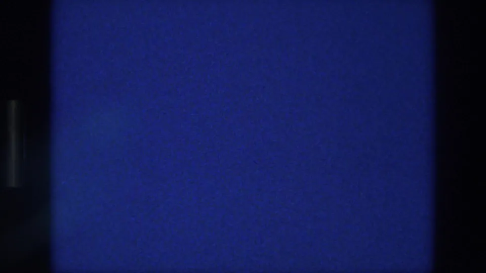 1976 Athens 8mm frame with a mostly empty blue sky, visible film grain, light specks, and dark contact-sheet divider edges.