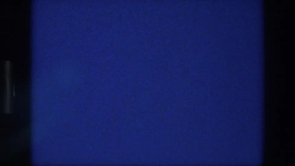 1976 Athens home-movie still showing saturated blue sky, subtle grain, a few dust marks, and dark borders from the scan layout.