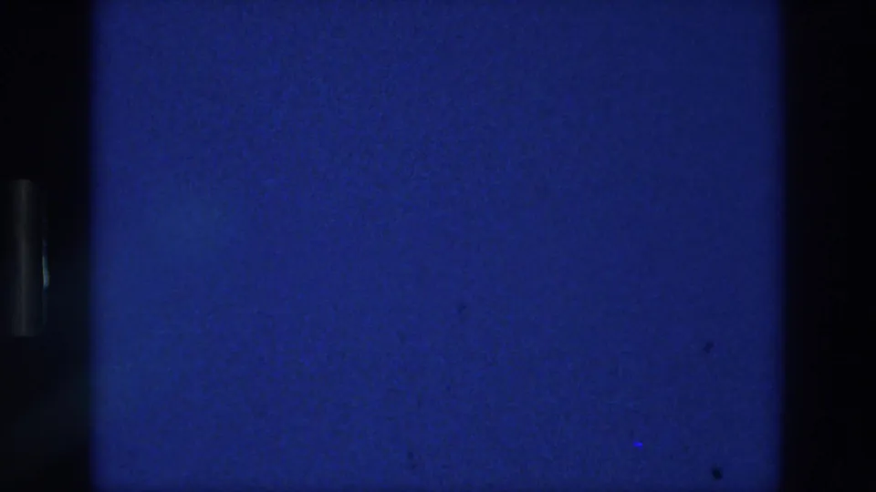 1976 Athens 8mm frame with blue screen texture, a dark vertical band, grain, and small exposure marks.