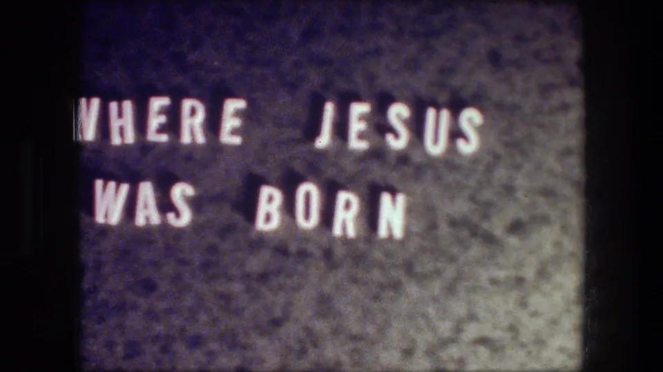 Close view of a filmed title card reading 'WHERE JESUS WAS BORN' in the 1976 Bethlehem travel clip.