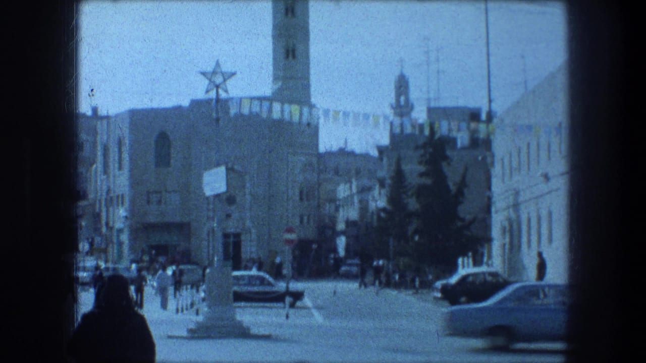 1976 8mm Bethlehem street scene with pedestrians, passing cars, a tower, hanging banners, and a large star symbol on a building.