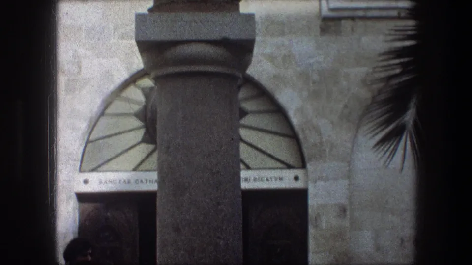 Tight 1976 Bethlehem frame showing the statue pedestal, arched entry, palm fronds, and partial inscriptions near the base.