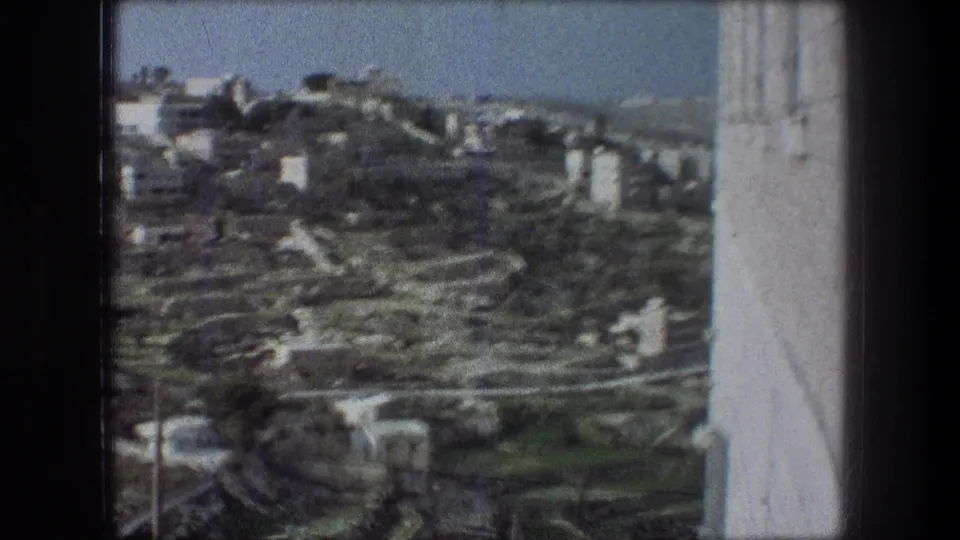 1976 Bethlehem 8mm frame showing a soft distant hillside town view beside a pale wall edge.
