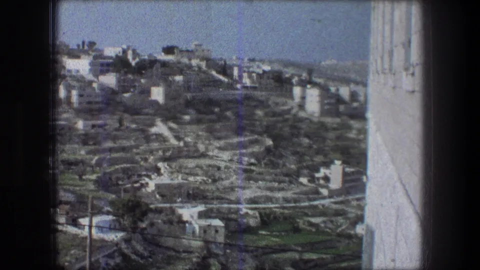 1976 8mm frame identified as Bethlehem, showing a high-angle view over pale buildings and terraced hillside roads.