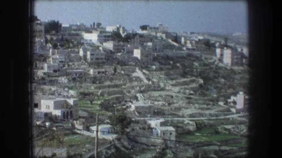 Elevated 1976 travel view identified as Bethlehem, with clustered pale masonry buildings across terraced hillsides.