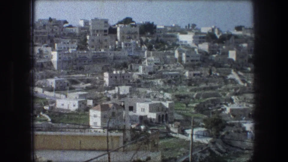 1976 8mm overlook identified as Bethlehem, showing hillside buildings, foreground wires, terraced roads, and open sky.