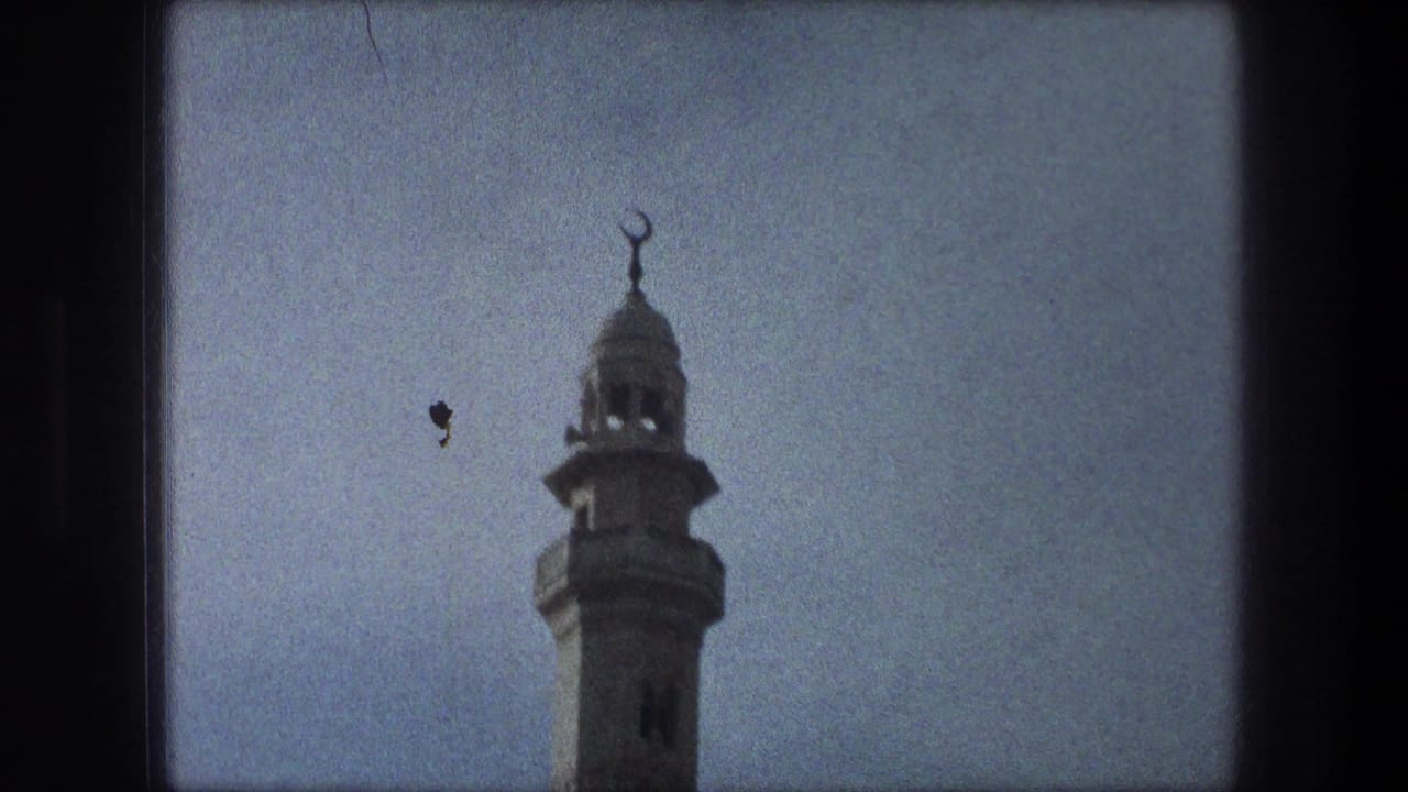 1976 Bethlehem 8mm view of a mosque minaret with crescent finial, framed from below against a pale sky.