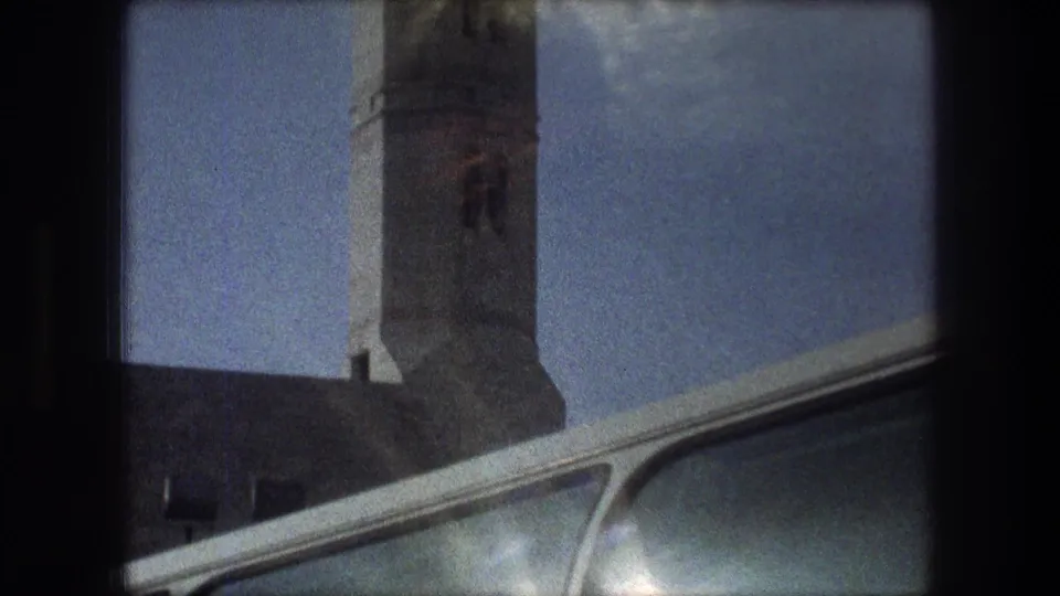 1976 Bethlehem 8mm frame with the minaret above a low roofline and a partial car window crossing the foreground.