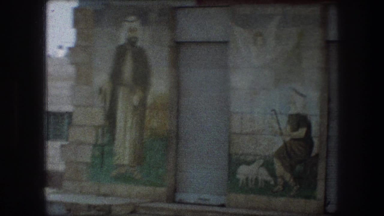 Painted religious figures on a wall beside a gray metal door.