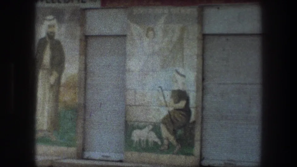 The 8mm frame shows a painted religious scene with a shepherd motif and sheep beside a plain metal door.