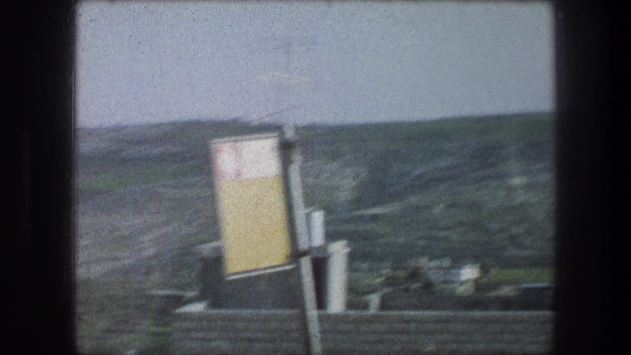 1976 Bethlehem hillside scene with a yellow-and-white sign, rooftops, chimney or vent pipes, and green slopes beyond.