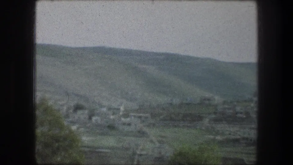 1976 8mm travel view near Bethlehem showing rolling hills, scattered buildings, and a hazy valley seen from a moving car.