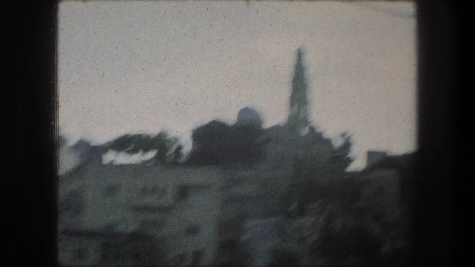 Bethlehem 8mm travel frame showing low town buildings and a distant domed tower, likely a church or landmark, in soft silhouette.