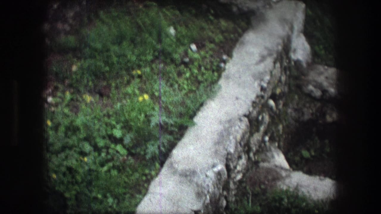 1976 Bethlehem 8mm frame looking down over a pale stone edge, green ground cover, and rough stones.