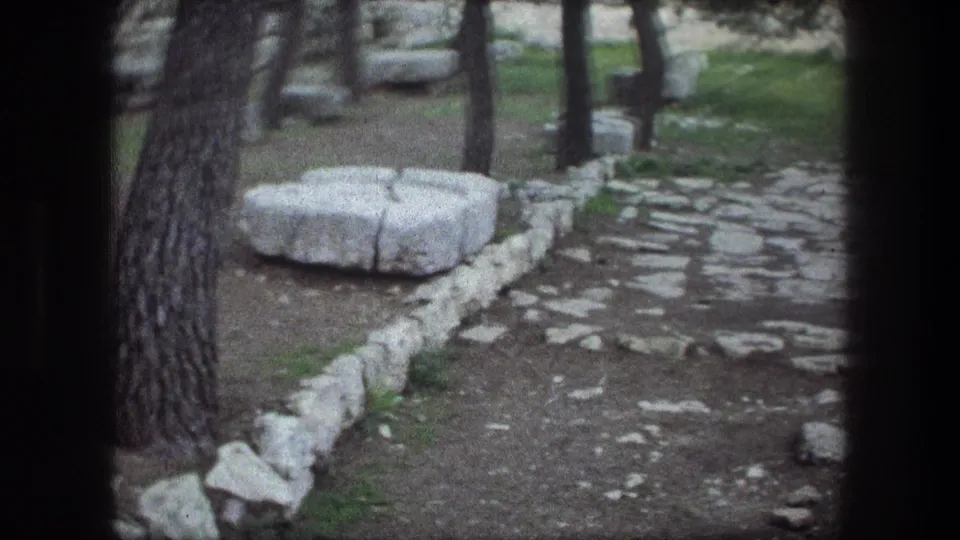 Visitor-shot 1976 Bethlehem view of a cobblestone path bordered by trees, grass, rough stones, and large carved blocks.