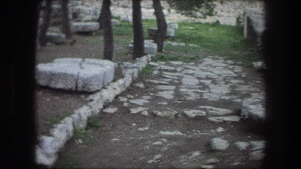 Soft 8mm frame from Bethlehem in 1976 looking along a stone path with trees, grass, and rough masonry edging.