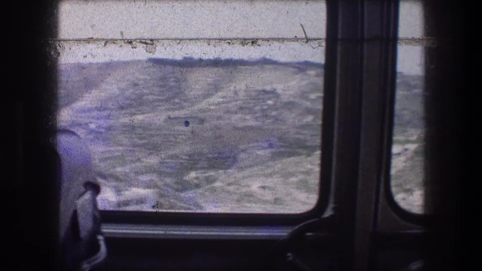 View from inside a moving vehicle toward rolling hills near Bethlehem, with dark window framing and faded 8mm color.