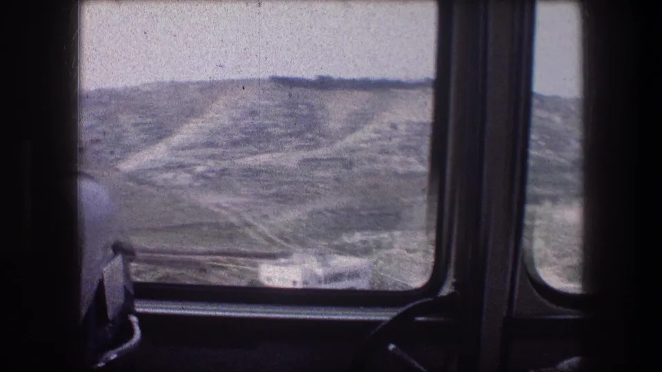 A 1976 vehicle-window view across pale, rugged hills in the Bethlehem area, framed by the interior of the transport.