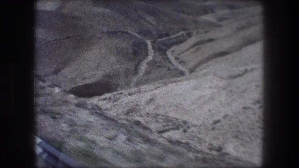 The clip ends on a dry Bethlehem mountain slope with a road edge and valley-like terrain seen from the moving vehicle.
