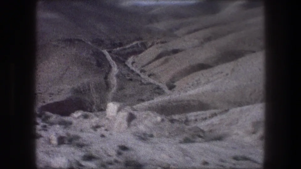 Bethlehem-area ravine and hillside terrain appears through dark 8mm borders, with pale rocks and scrub visible in the foreground.
