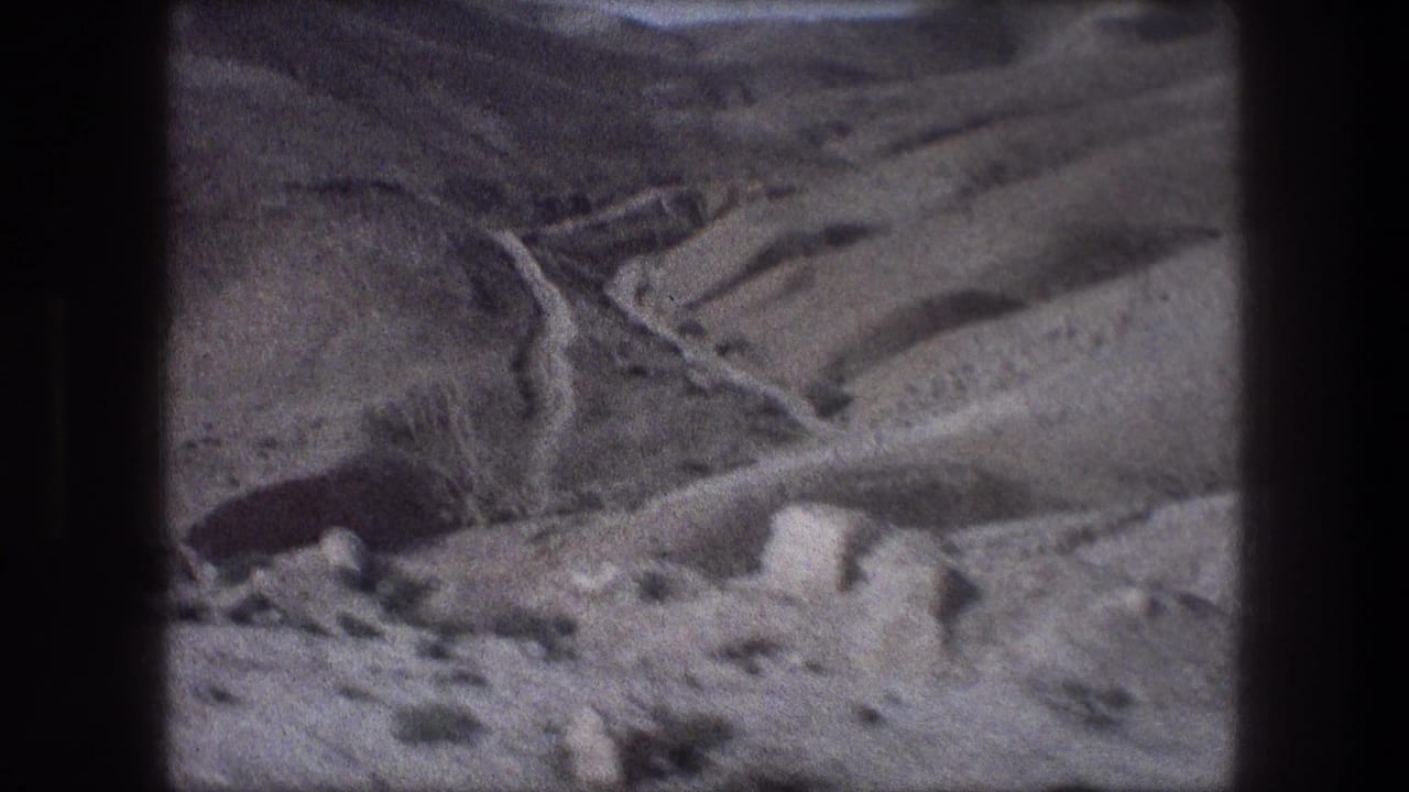 Winding dirt road crossing dry rocky hillsides with sparse scrub.