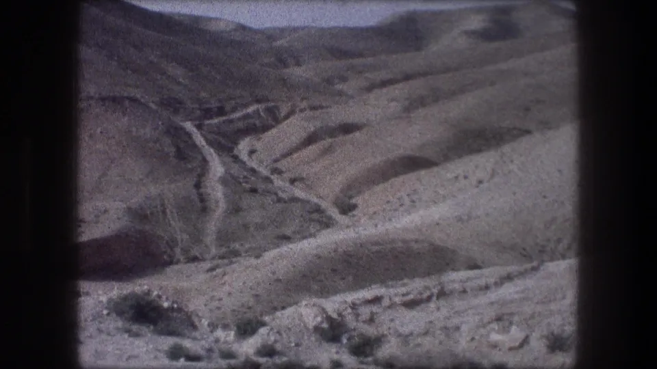 1976 home-movie view near Bethlehem of an unpaved road snaking through barren mountain slopes.