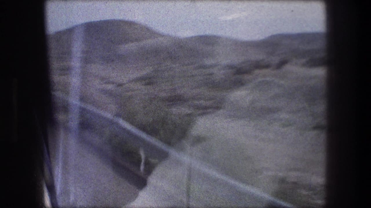 Vehicle-window view near Bethlehem with a roadside guardrail, paved edge, and dry hills receding into haze.