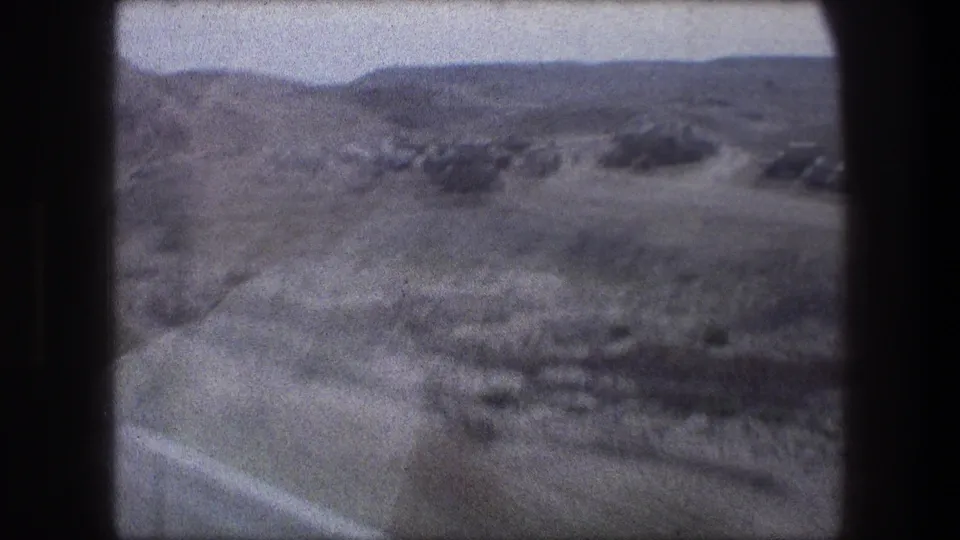 Soft 8mm frame near Bethlehem showing open dry fields, low hills, and motion blur from travel.